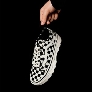 Schwarz-weißer kariert Schuh in Hand